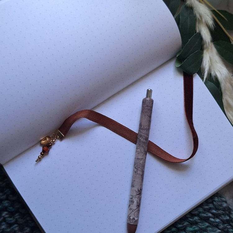 Open dot grid journal with a pen and decorative flowers on a textured surface